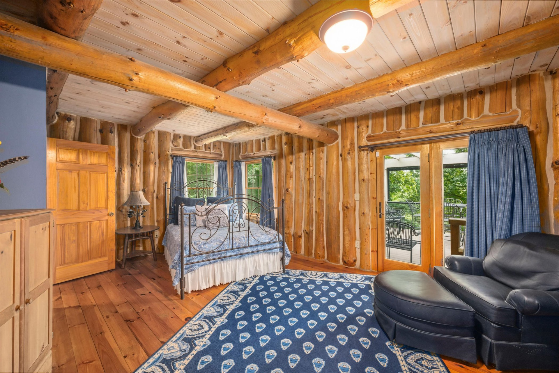 Guest bedroom with log walls and doors to the deck