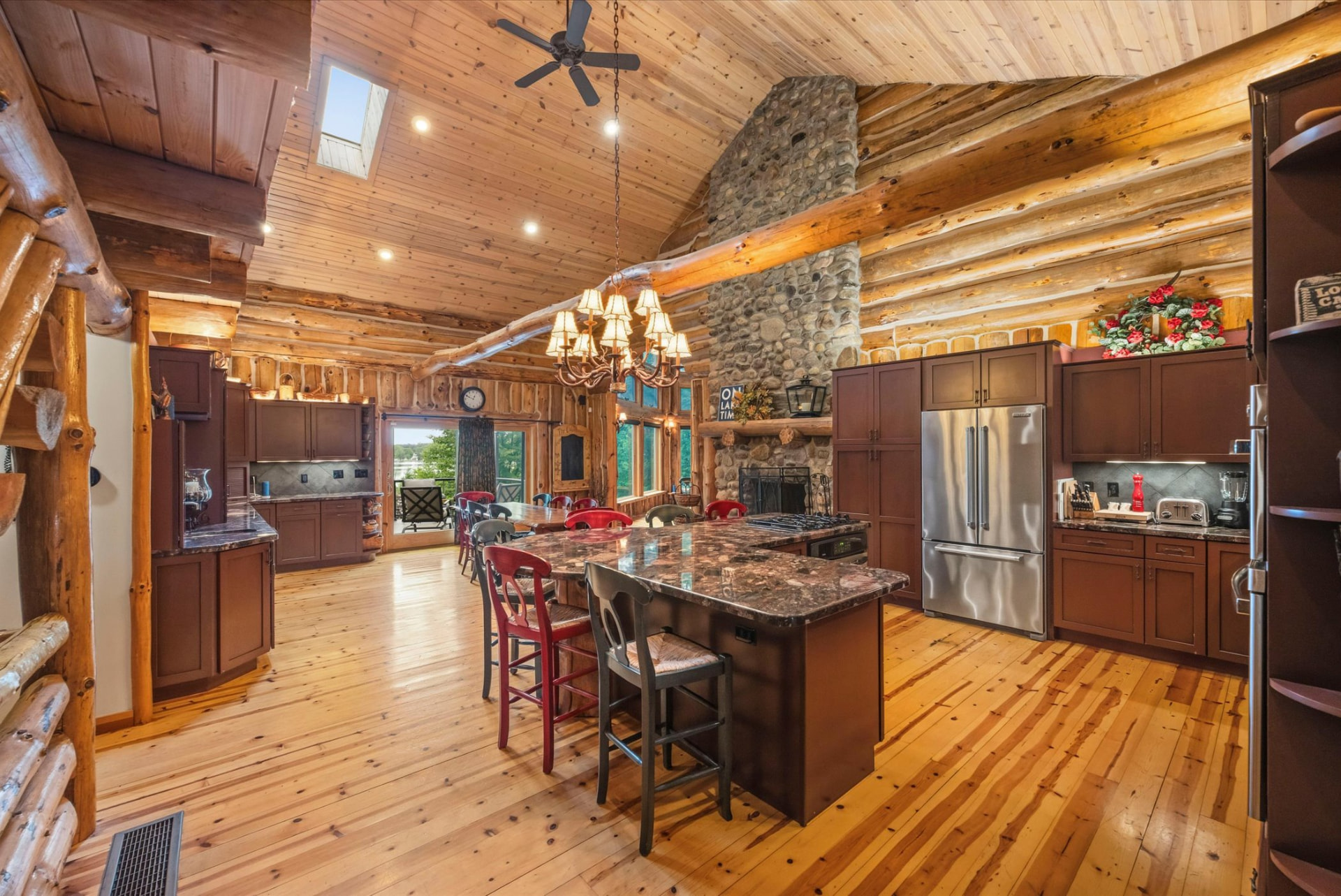 Chef's kitchen with granite island, gas cooktop and river-rock fireplace beyond