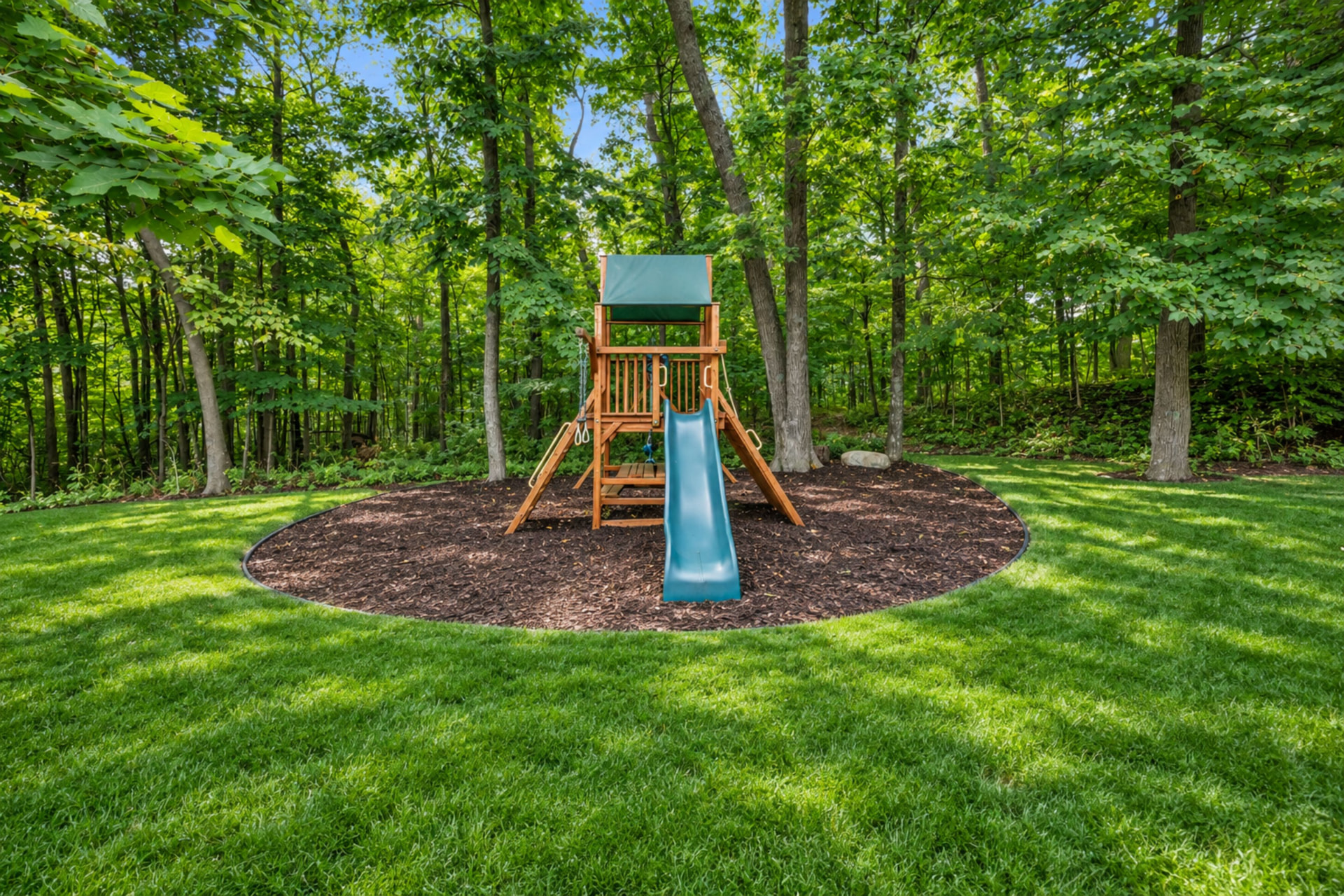 Wooded play area at the edge of the lawn